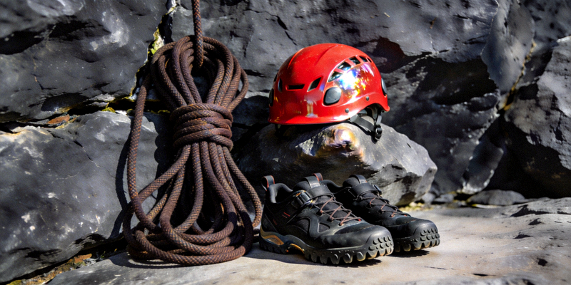 专业登山装备在岩石上展示，包括绳索、头盔和攀岩鞋